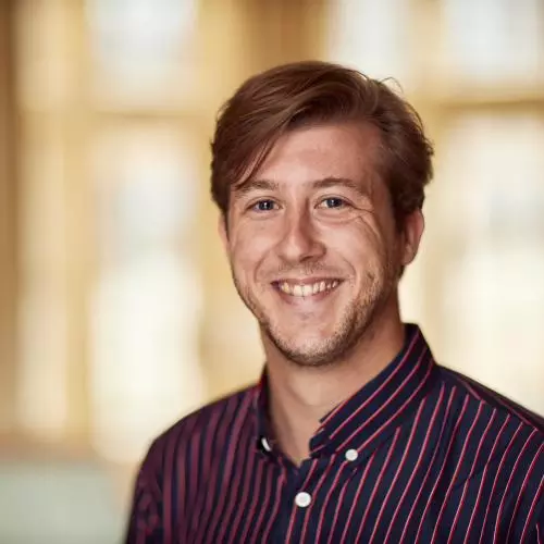Dirk Witteveen has short hair, wearing a black and red striped shirt smiling at the camera.