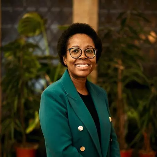 Zamakhanya Makhanya has afro hair, with black rimmed glasses, weating a green jacket smiling at the camera.