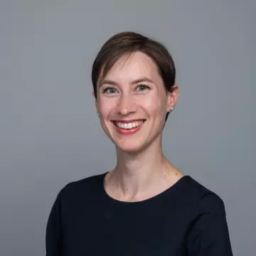 Inge Vallance has short dark hair and is smiling at the camera. She is wearing a black top.