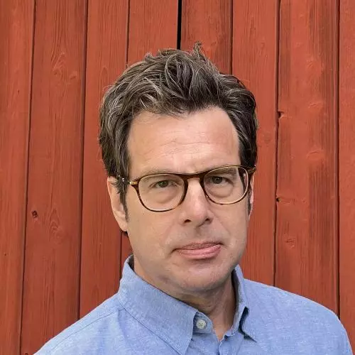 Kenneth Nelson is wearing glasses and a blue shirt looking directly at the camera.