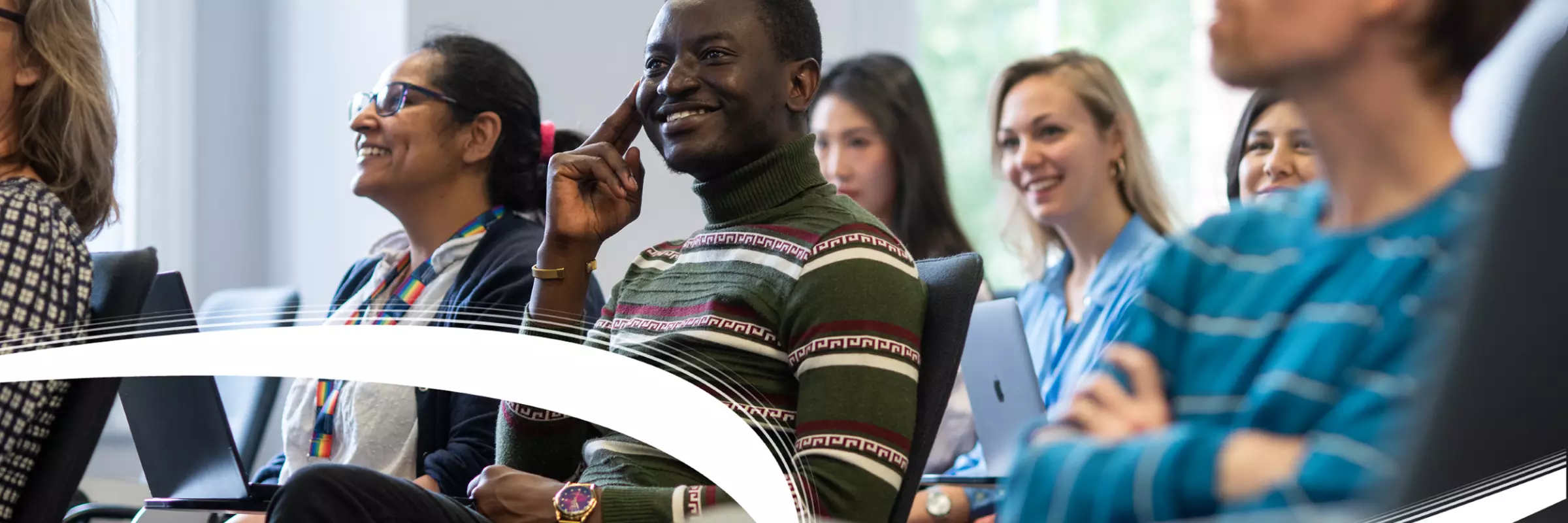 Students sitting in a seminar room, looking forward and smiling. Credit: John Cairns Photography