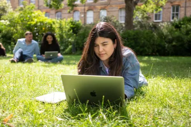 DSPI students looking at laptops in the garden at Barnett House
